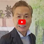 Video thumbnail: smiling man in a dark blazer against a green forest backdrop, with a play button overlay