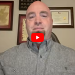 Video thumbnail: bald man in a gray shirt speaking, with framed diplomas on the wall behind him.
